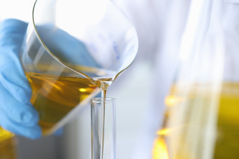 scientist-chemist-pouring-oil-from-flask-into-glass-closeup-quality-control-edible-oils